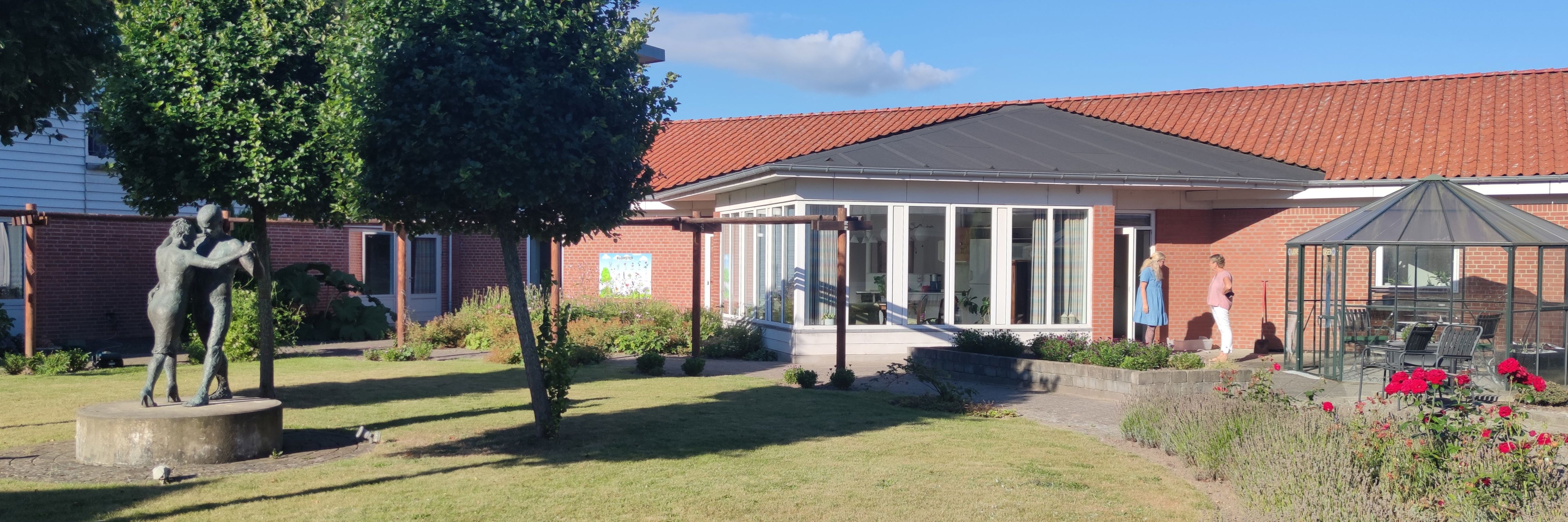 Billede af haven på et plejecenter, med en skulptur med et dansende par.