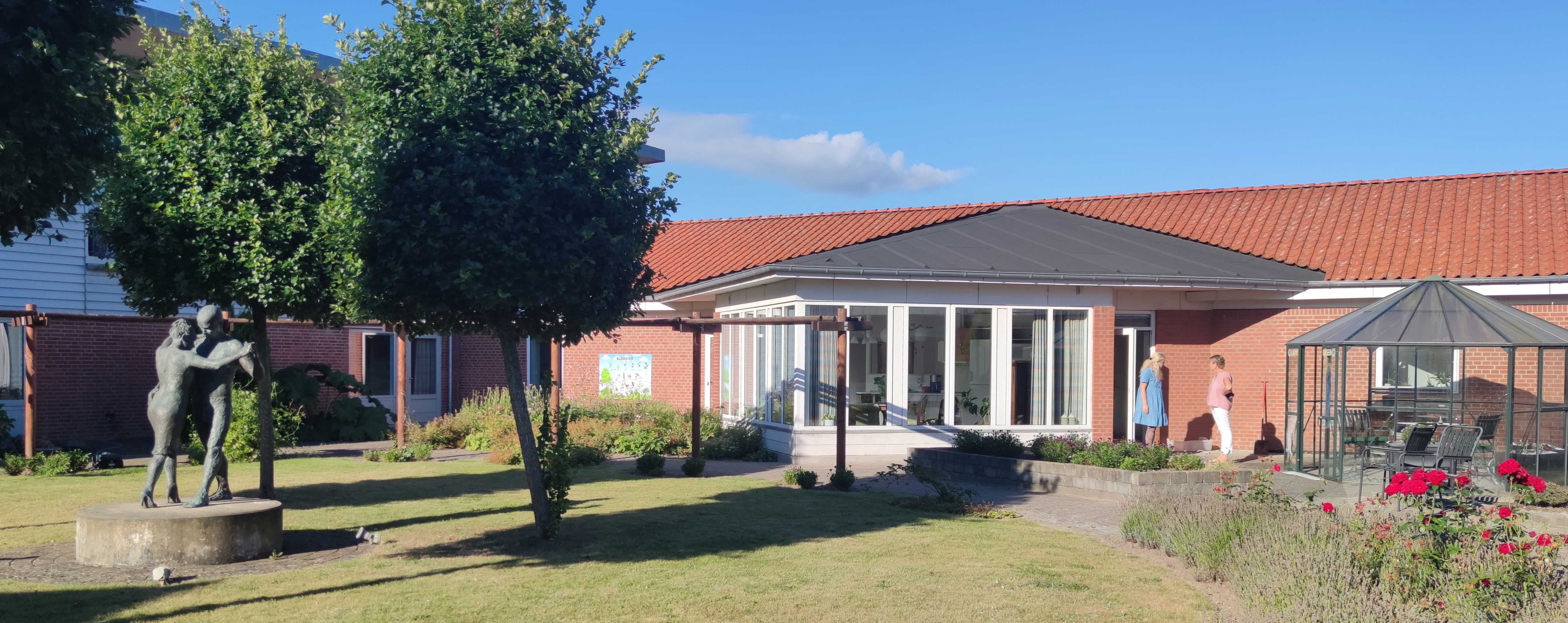 Billede af haven på et plejecenter, med en skulptur med et dansende par.